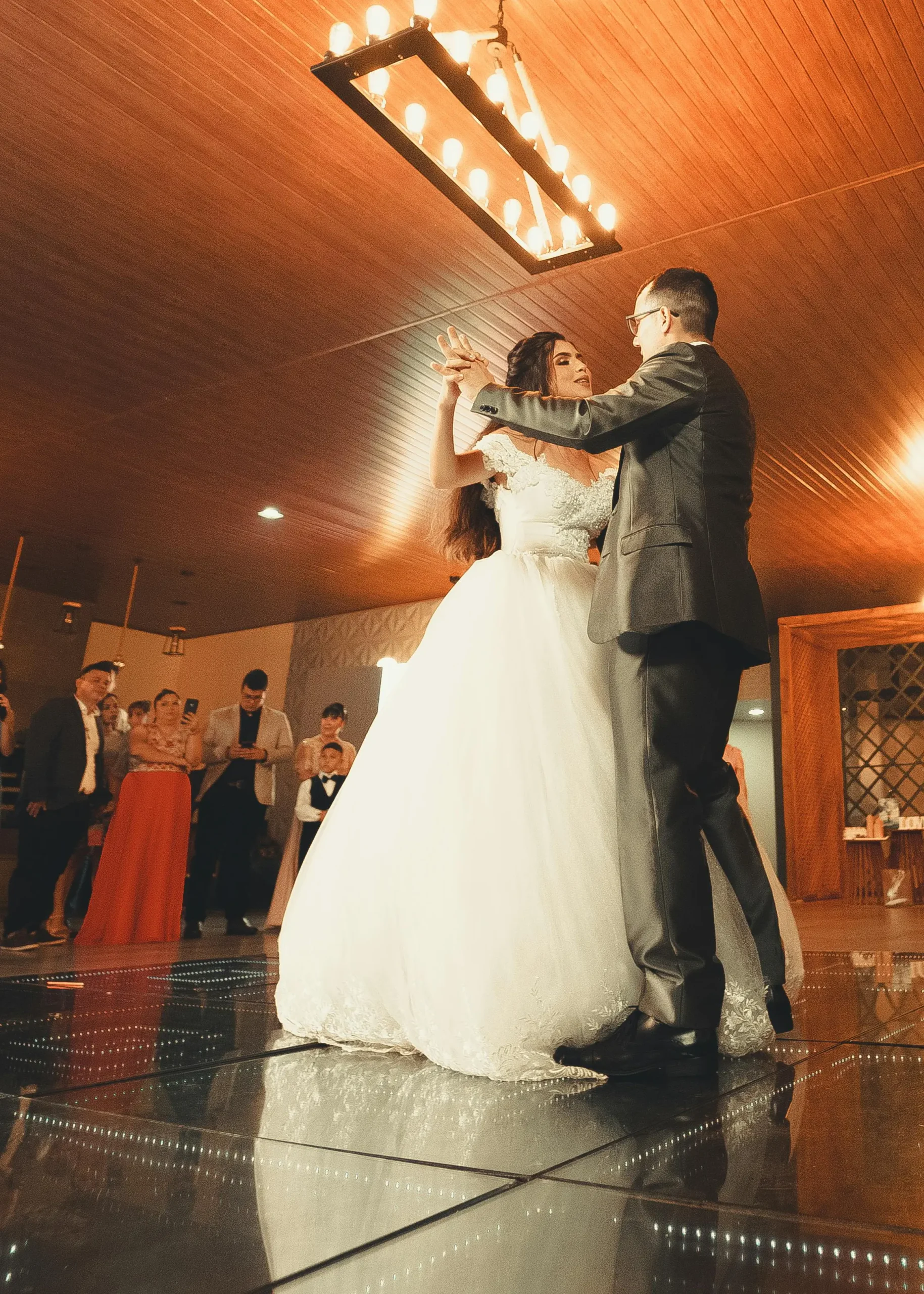 Bride and groom's first dance with guests watching from the edge of the dance floor