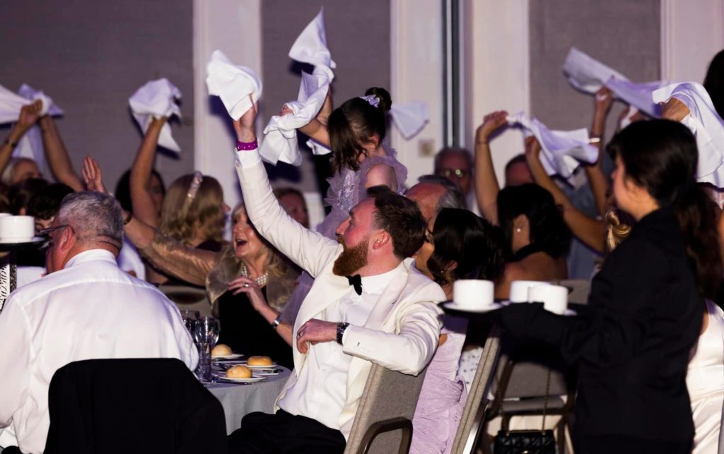 Wedding guests waving white napkins above their heads during the wedding