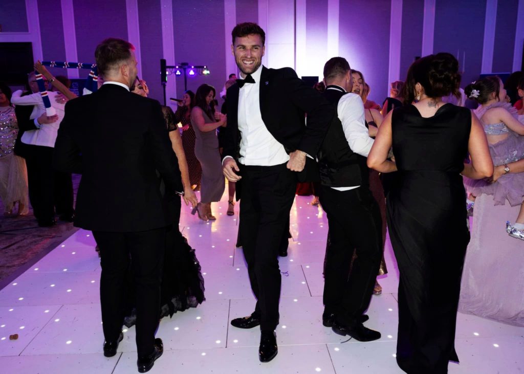 Guests in black tie dancing on a white LED dance floor